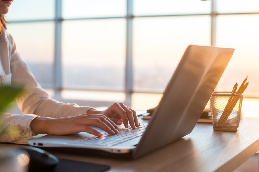 Eine Geschäftsfrau, die von zu Hause aus arbeitet und am Laptop schreibt,